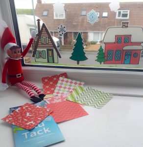 elf on the shelf decorating the window with stickers